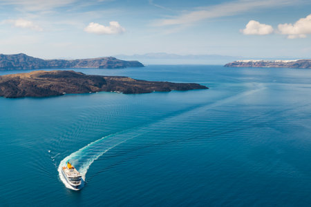 Ferry arrives at the port of Santorini Island, Greece. Blue sea and the blue sky with clouds. Summer seascape. Travel and summer vacation conceptの写真素材
