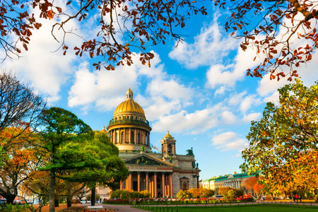 Saint Isaac's Cathedral in Saint Petersburg, Russia. Autumn cityscape with yellow trees in the park at sunsetの写真素材