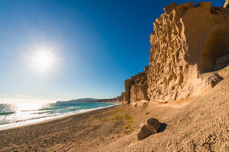 Volcanic cliffs on Vlichada beach, Santorini island, Greece. Yellow sand and the blue sea. Famous travel destinationの写真素材