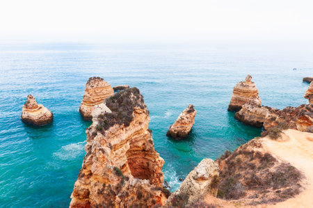 Algarve, Portugal. Sandstone rocks and turquoise water in mIsty morning on the shore of Atlantic oceanの写真素材