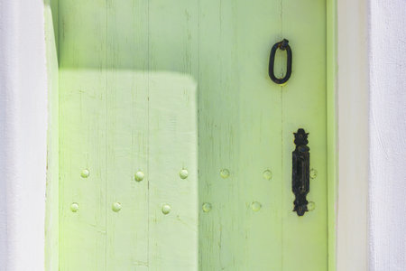 Green-painted vintage wooden door with metal handle close up. Cycladic architecture in Santorini island, Greece.の写真素材