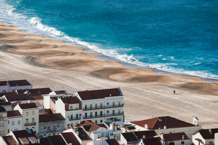 View of the sandy beach and ocean waves in Nazare, Portugal. Traditional portuguese architecture on the coast of Atlantic oceanの写真素材
