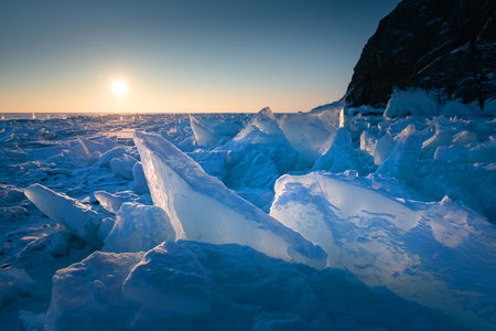 Blue ice on Baikal lake at sunrise. Winter landscape. Khoboy cape of Olkhon island, Baikal, Siberia, Russia.の写真素材