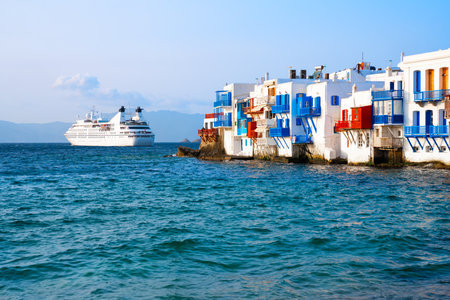 White architecture of Mykonos town and view of Little Venice bay in Mykonos island, Greece. Cruise ship near the island. Blue sea and the blue sky at sunsetの写真素材