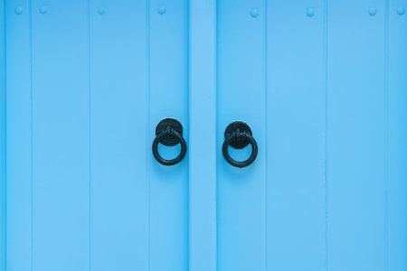 Blue-painted vintage wooden door with metal handles close up. Cycladic architecture in Santorini island, Greece. Architecture detail abstract backgroundの写真素材