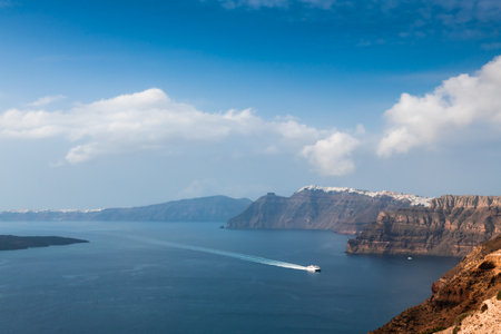 Panoramic view of Santorini island, Greece. Ferry sails to the port. Blue sea and the blue skyの写真素材