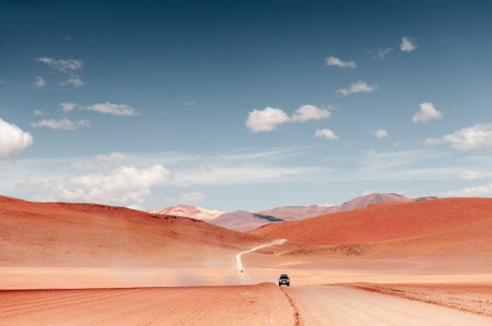 Altiplano plateau, Bolivia. Off-road cars driving on the road in the desert. View of the volcanoes and the blue sky with clouds. South America summer landscapesの写真素材