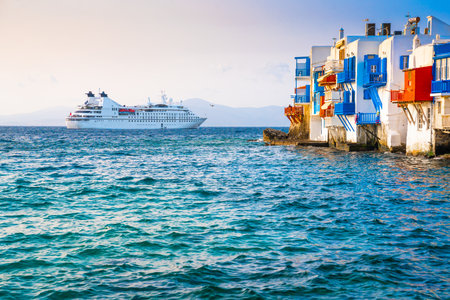 White architecture of Mykonos island, Greece. Big cruise ship near the island. Blue sea and the blue sky at sunset. Famous travel destinationの写真素材