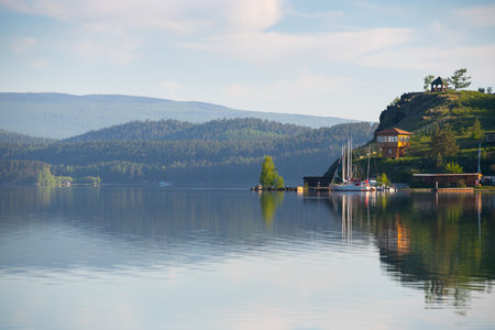 Beautiful lake with clear blue water at sunrise. Mountains are reflected in the calm water surface. Turgoyak lake in Southern Urals, Russia. Summer landscape.の写真素材