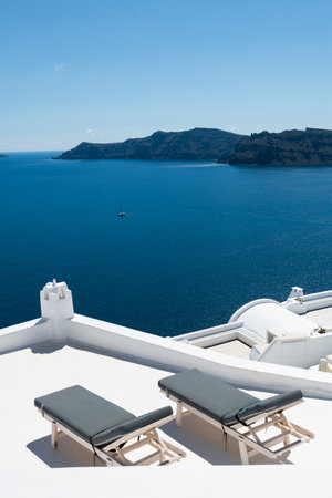 Santorini island, Greece. Two chaise lounges on the terrace with sea view. Travel and summer vacation conceptの写真素材