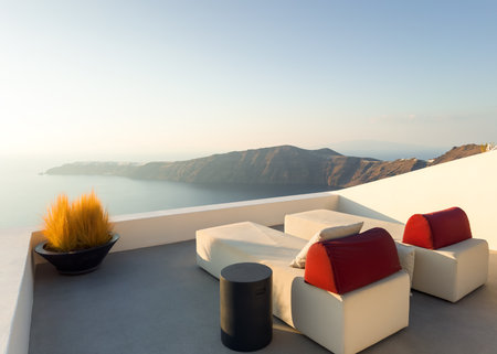 White architecture in Santorini island, Greece. Two chaise lounges on the terrace with sea view at sunset.の写真素材