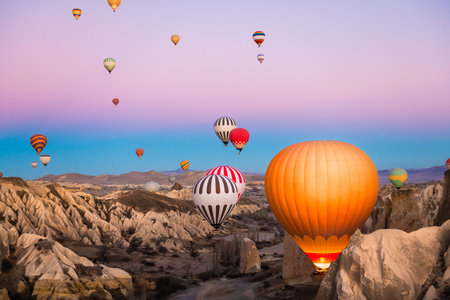 Colorful hot air balloons flying over the mountains in Cappadocia, Turkey. Beautiful landscape at...