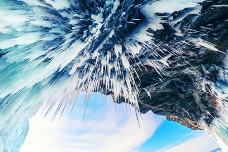 Ice cave with icicles in Baikal lake at sunset. Icicles on the rocks. Bottom up view. Winter...