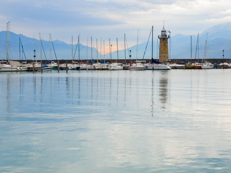 Beautiful sunset at Garda lake, Italy. Lighthouse in the port of Desenzano del Garda. Alps mountains in the background.の写真素材