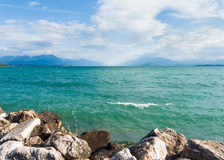 Beautiful shore of Garda lake with turquoise water and Alps mountains in the background. Desenzano del Garda, Italy. Famous travel destinationの写真素材