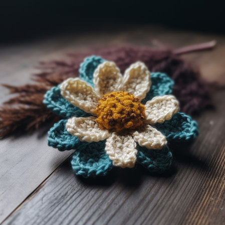 Close-up of a charming crochet flower. Teal and cream petals surround a golden center.の写真素材