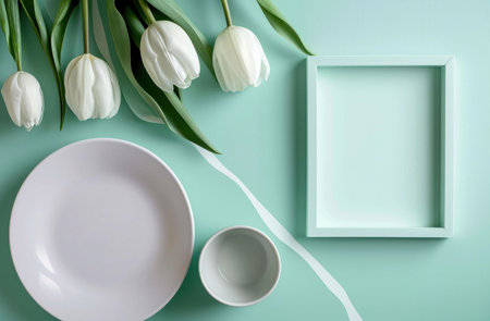 A stylish flatlay featuring white tulips, a plate, and bowl against a mint background. Perfect for springtime themes.の写真素材