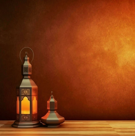 Two ornate lanterns, one large and one small, sit on a wooden table against a brown background. The larger lantern is lit, casting a warm glow.の写真素材