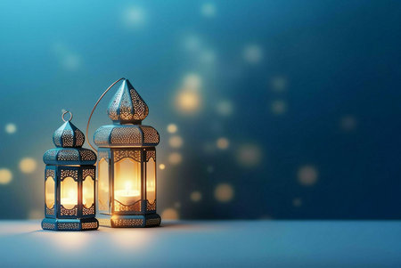 Two ornate lanterns with intricate designs stand lit against a blurred blue background. The lanterns illuminate the scene with warm light, creating a peaceful and festive ambiance. The image captures the spirit of celebration and tradition.の写真素材