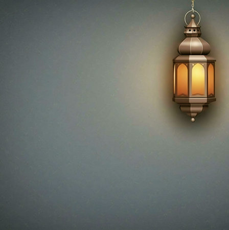 A traditional Islamic lantern hanging on a plain gray wall, lit up and casting a warm glow. The intricately designed and warm light create a beautiful and festive atmosphere.の写真素材