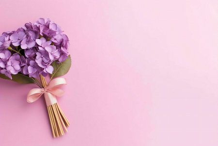 A vibrant purple hydrangea bouquet is arranged on a soft pink background, creating a delicate and romantic composition.の写真素材