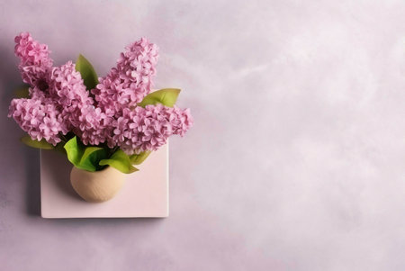 A delicate lilac bouquet in a small vase on a pale pink background. A minimalist springtime still life.の写真素材