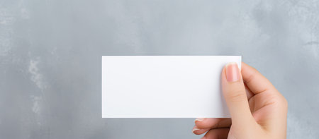 A hand holding a blank white card against a gray background, ready for your message.
