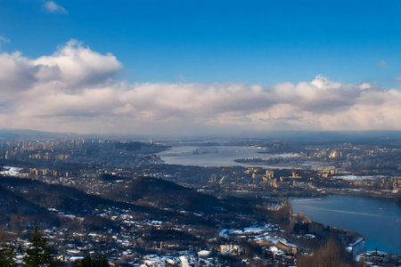 Stunning aerial view of a coastal city during winter, showing a vast expansion of buildings, water, and mountains under a brilliant blue sky.の写真素材