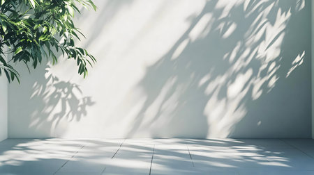 A tranquil image of a minimalist room. Sunlight casts leaf shadows on a white wall and floor.