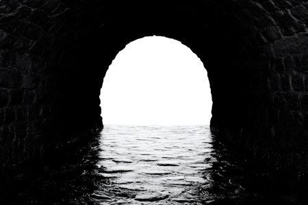 A monochrome image depicting a stone archway over water, symbolizing transition and mystery.の写真素材