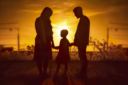 Silhouetted family at sunset, holding hands, showing love and unity.の写真素材
