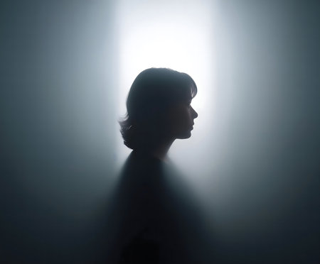 A woman's silhouette is seen through a hazy light, creating a mysterious and introspective mood.の写真素材