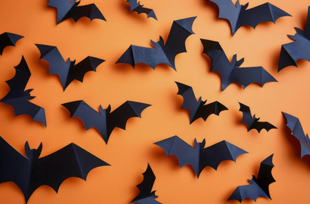 Black paper bats on an orange background. Halloween decoration.