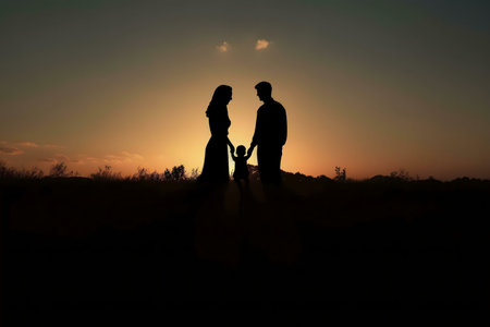 A family of three silhouetted against a stunning sunset. Love, unity, and togetherness.の写真素材