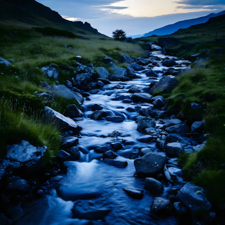 A tranquil stream flows through a mountain valley at twilight. Serene and peaceful.の写真素材