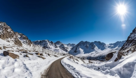 A winding road through a snow covered mountain range on a bright sunny winter day.の写真素材