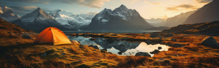 Orange tent near a lake, reflecting the mountains at sunset.の写真素材