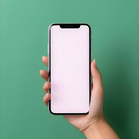 A hand holds a smartphone with a blank screen against a green background.の写真素材