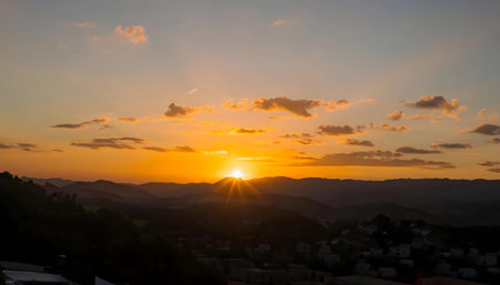 Stunning sunset view over a hilly landscape. Orange and gold hues dominate the sky.の写真素材