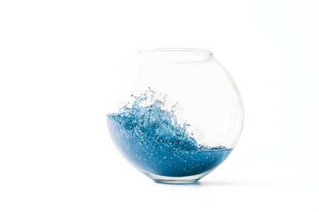A captivating image of a blue liquid splashing in a glass bowl against a white background. The dynamic composition is both artistic and visually striking.の写真素材