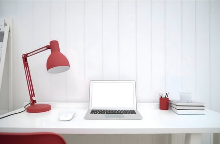Clean, minimalist workspace with a red desk lamp and laptop.の写真素材