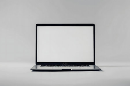 A clean, minimalist image featuring a laptop with a blank white screen against a neutral gray background.の写真素材