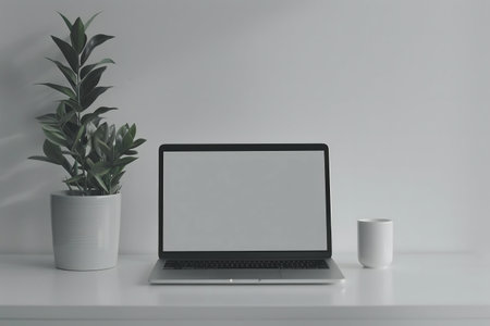 A clean, minimalist workspace featuring a laptop, plant, and mug.の写真素材
