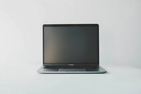 A sleek silver laptop sits on a plain white surface. Clean and simple.