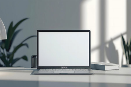 A clean, minimalist workspace featuring a laptop, plants, and sunlight streaming through a window.の写真素材