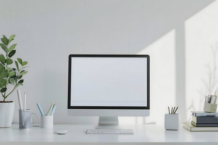 A pristine white desk features a computer monitor, keyboard, and mouse. Plants and organized...