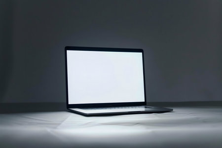 A laptop with a blank screen sits on a table in a dimly lit room.の写真素材