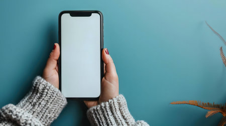 Hands holding a smartphone with a blank screen. Cozy winter sceneの写真素材
