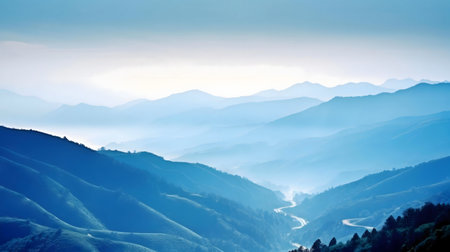Serene mountain vista, misty blue hues, winding road.の写真素材