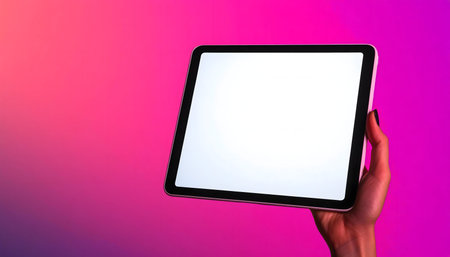 A hand holds a tablet with a blank white screen against a vibrant pink background.の写真素材